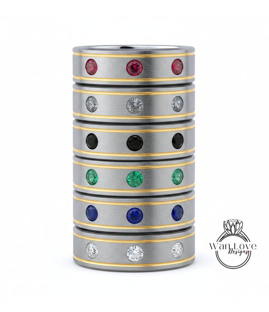 A stack of silver rings with colorful gemstones, including red, green, blue, and white stones, set in a metallic band with a yellow stripe.