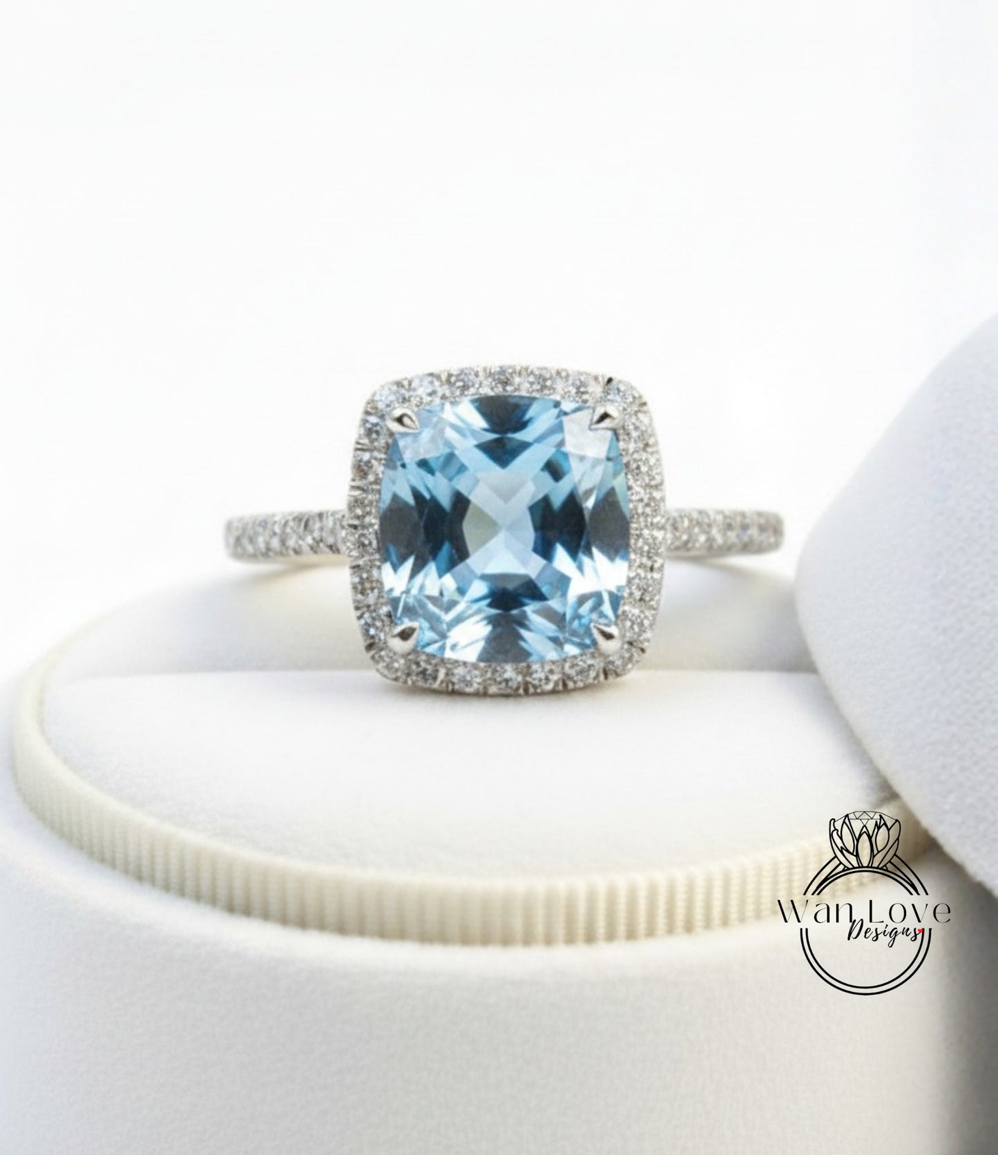 A stunning blue gemstone ring with a halo of diamonds, displayed on a white surface.