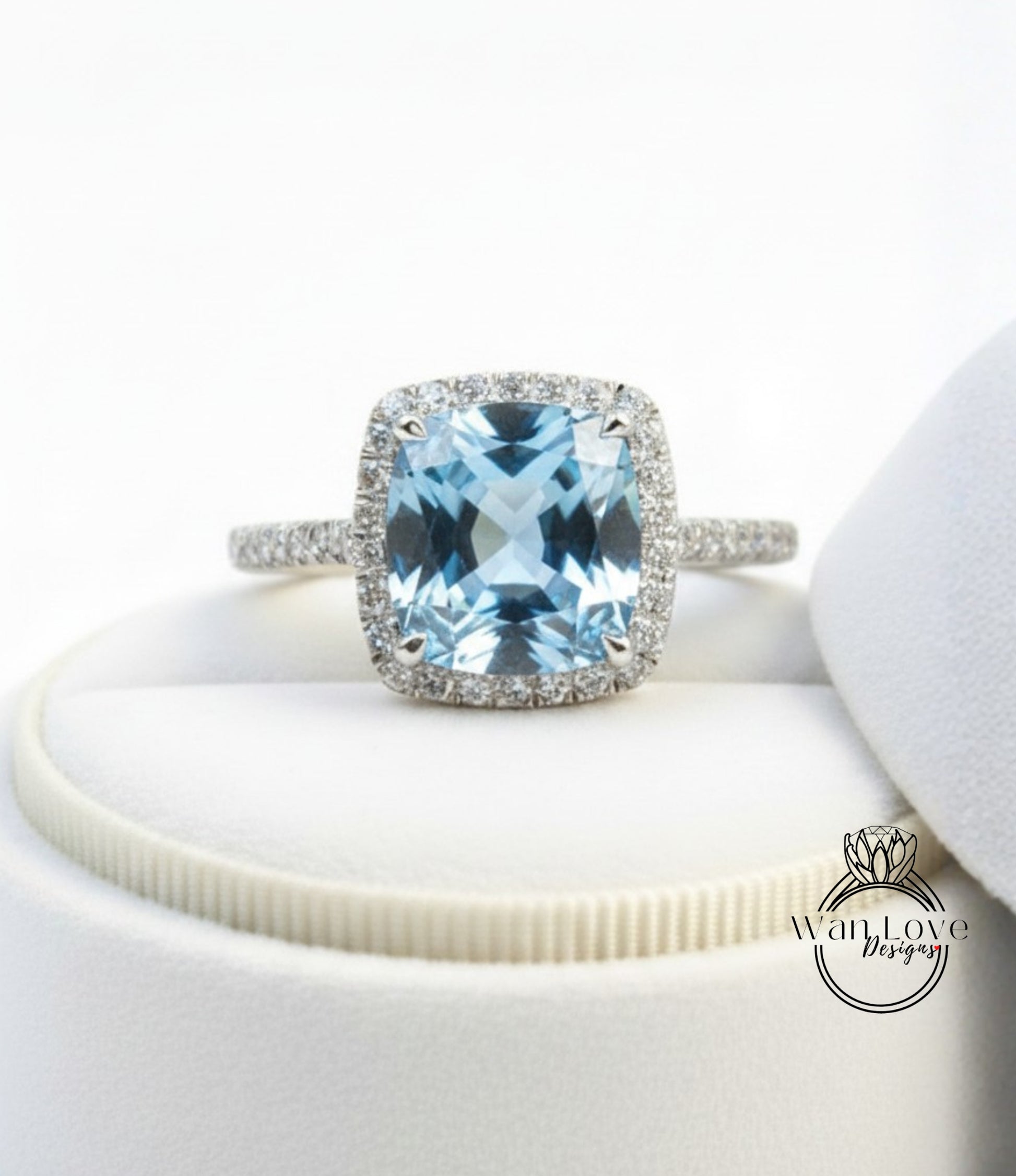 A stunning blue gemstone ring with a halo of diamonds, displayed on a white surface.