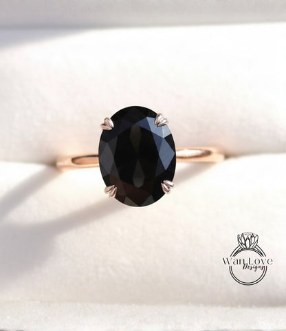 A gold ring with a large oval-shaped black gemstone, possibly a diamond, set in the center.