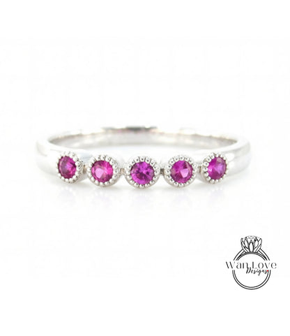 A silver ring with a row of five pink gemstones, each one larger than the one before, creating a visually appealing and elegant design.