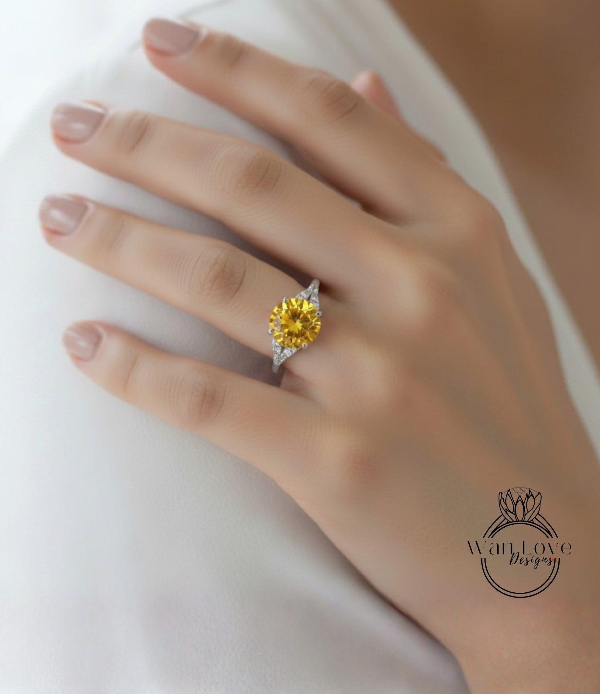 A close-up of a hand wearing a yellow diamond ring on the ring finger.