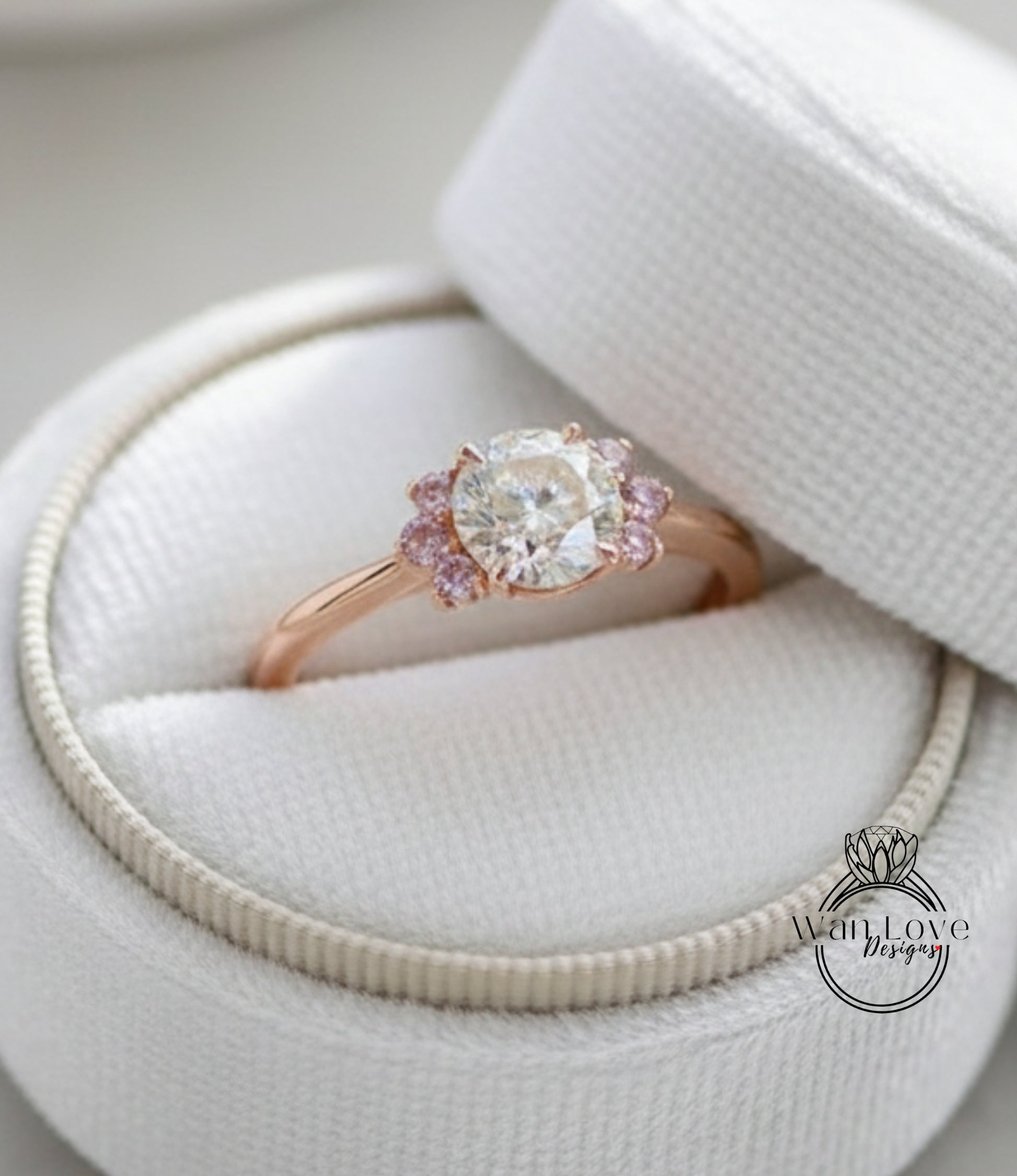 A close-up view of a beautiful engagement ring placed in a white box, showcasing the intricate details of the diamond and the delicate pink accents.