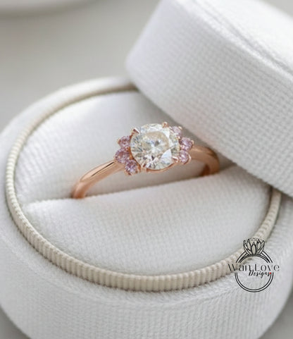 A close-up view of a beautiful engagement ring placed in a white box, showcasing the intricate details of the diamond and the delicate pink accents.