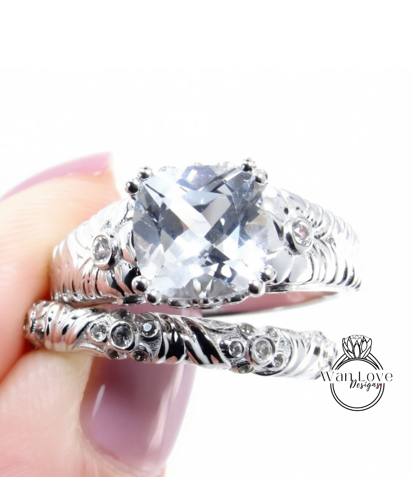 A close-up image of a person's hand holding a silver ring with a large, clear gemstone set in it.