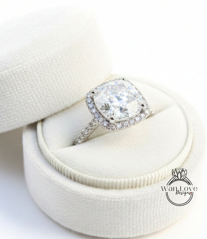 A large, sparkling diamond engagement ring is displayed in a white, velvet-lined box, showcasing its intricate design and sparkling gemstones.
