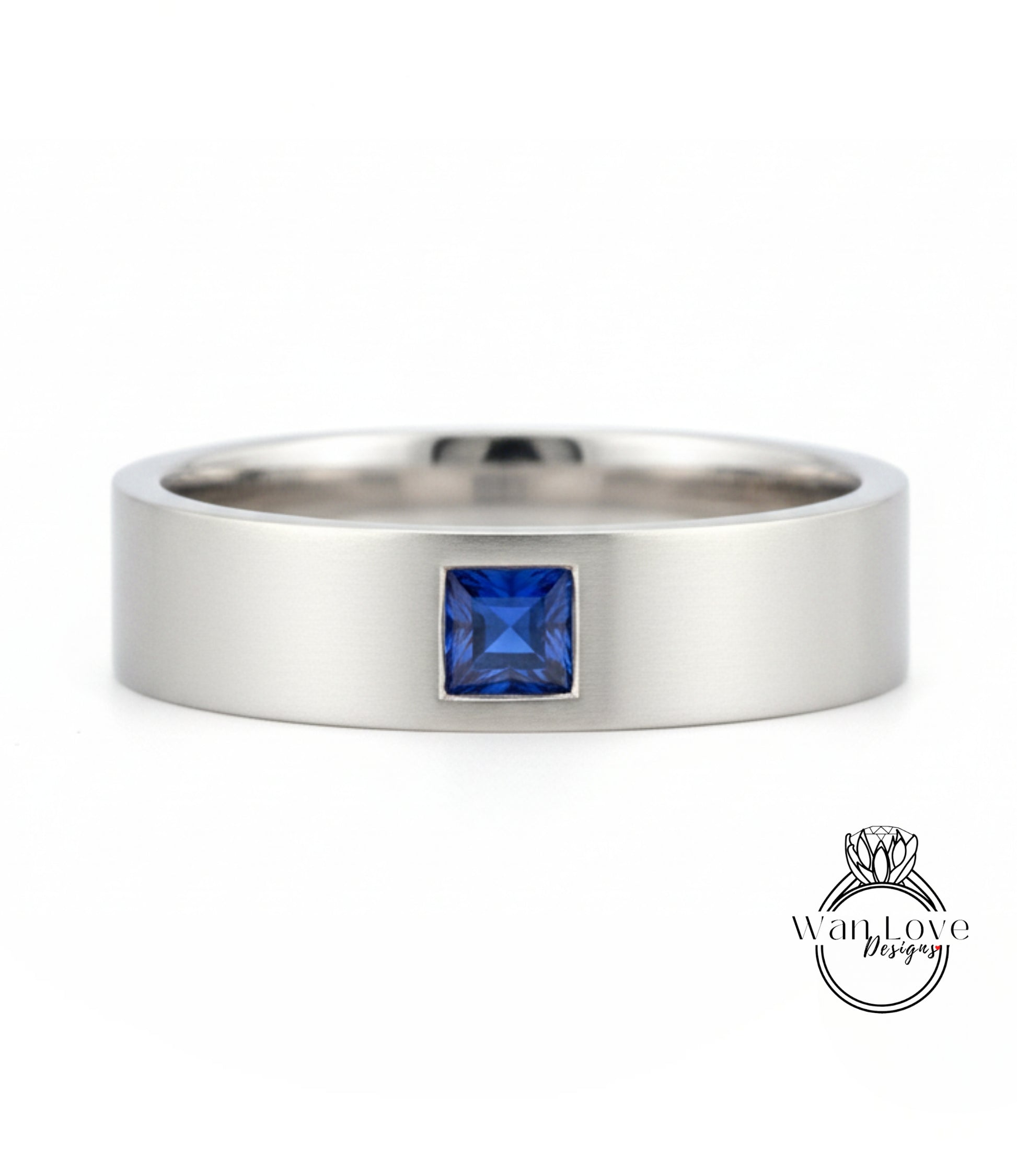 A silver ring with a blue gemstone, likely a sapphire, set in the center.