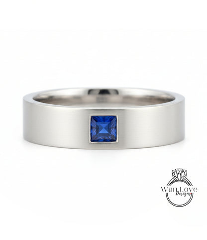 A silver ring with a blue gemstone, likely a sapphire, set in the center.