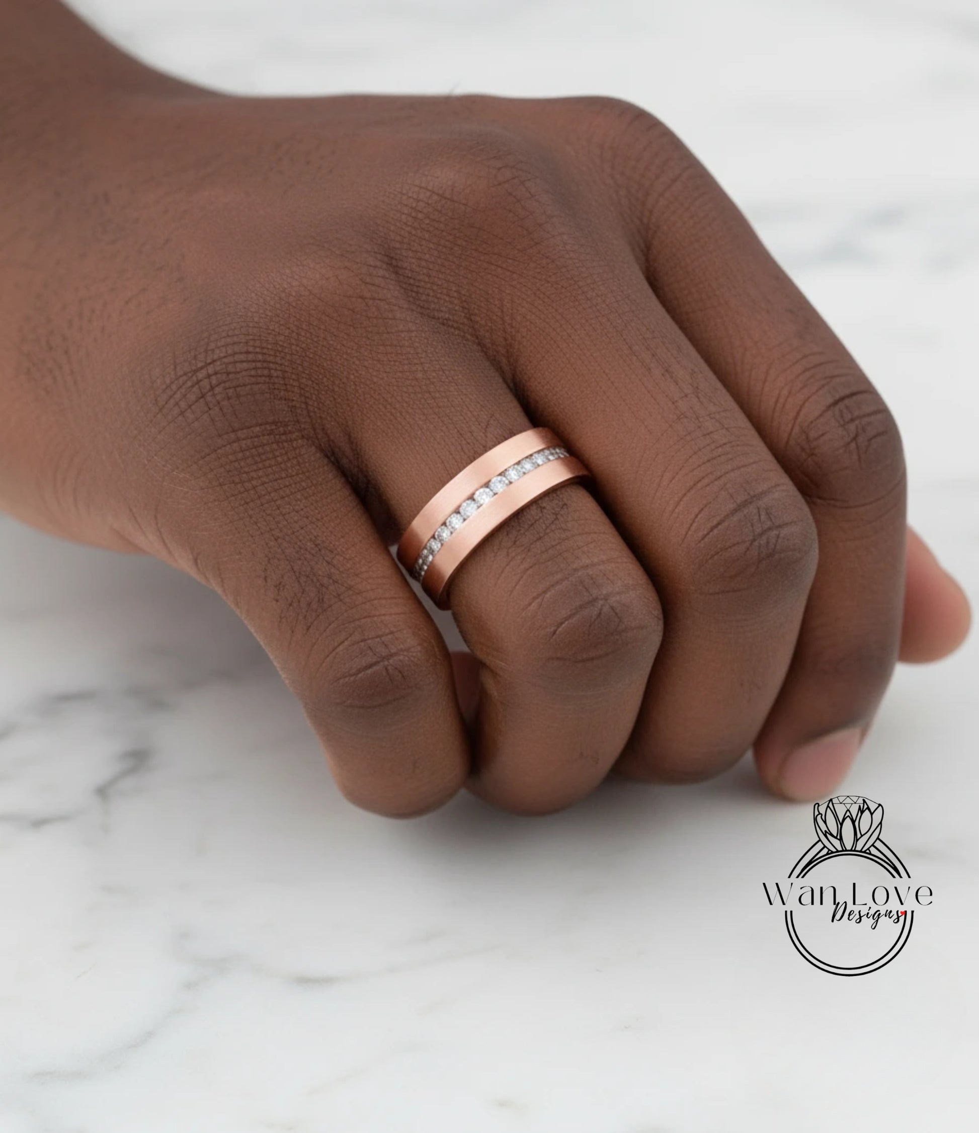 A close-up of a hand wearing a gold-colored ring with a diamond band.