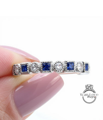 A close-up of a person's hand holding a ring with a row of blue gemstones on the band.