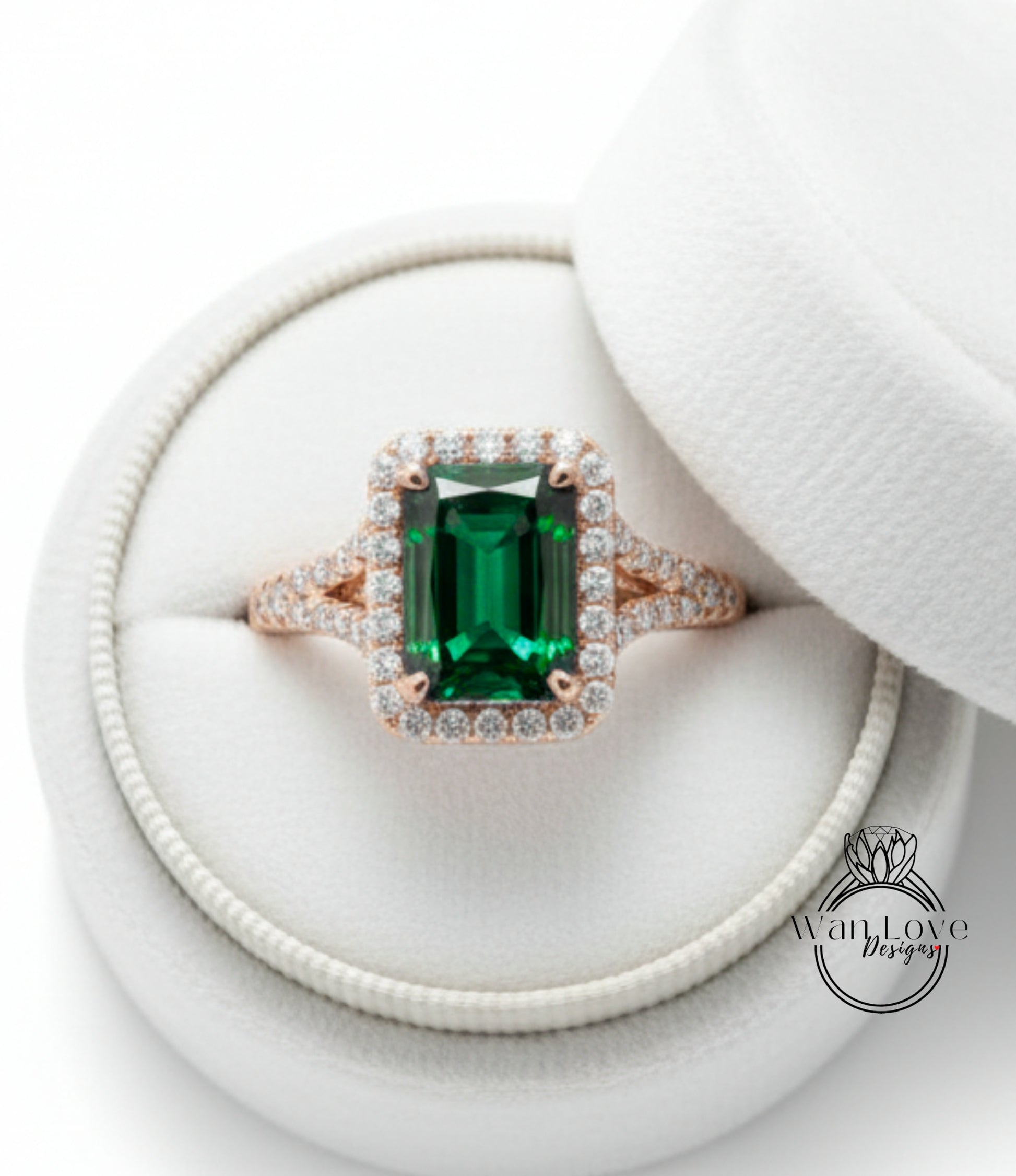A large, green gemstone ring with a halo of smaller diamonds set in a gold band, displayed in a white jewelry box.