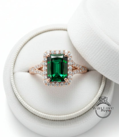 A large, green gemstone ring with a halo of smaller diamonds set in a gold band, displayed in a white jewelry box.