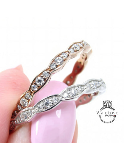 A close-up of a person's hand holding a ring with a pink gemstone and a silver ring with a similar design.