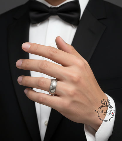 A close-up of a person's hand wearing a black tuxedo and a silver ring on the finger.