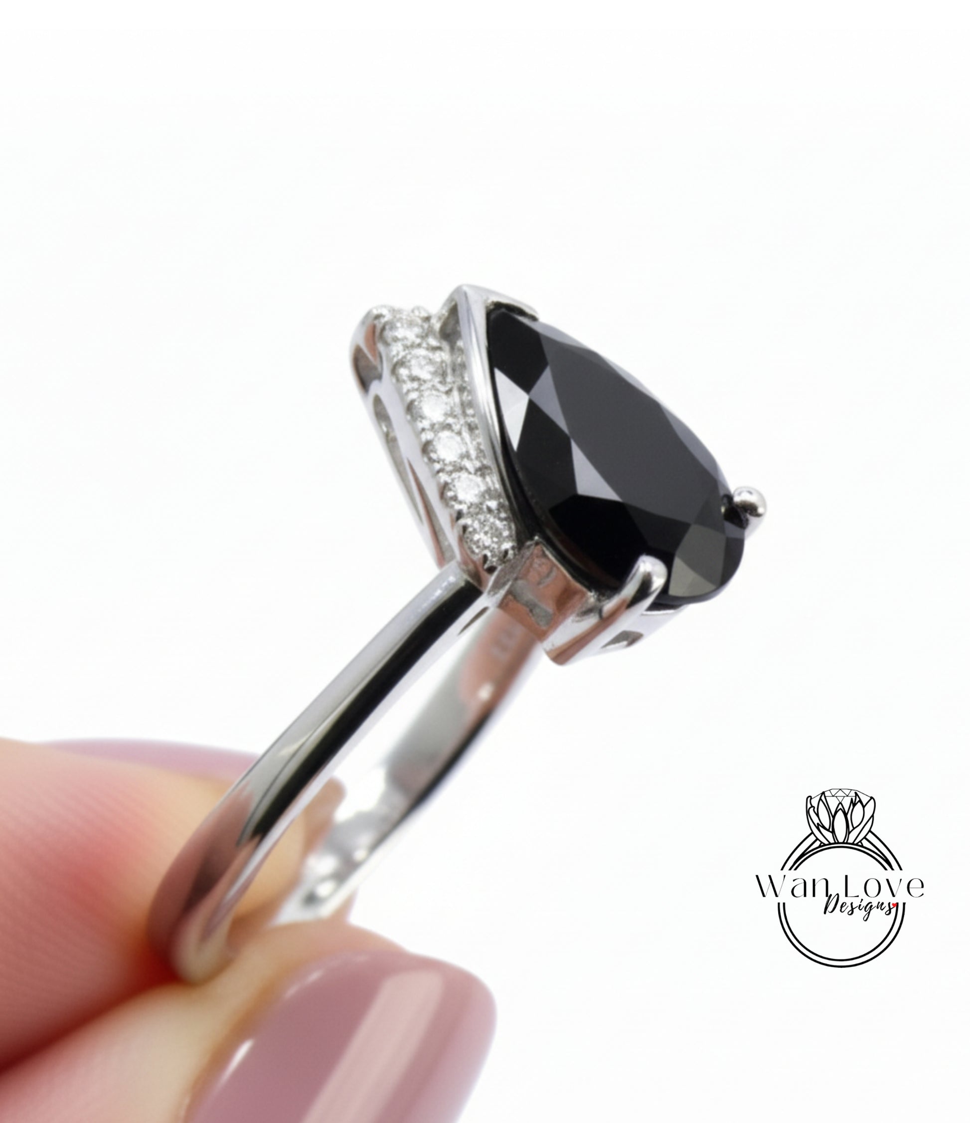 A close-up image of a person's hand holding a silver ring with a large black gemstone, likely a diamond.