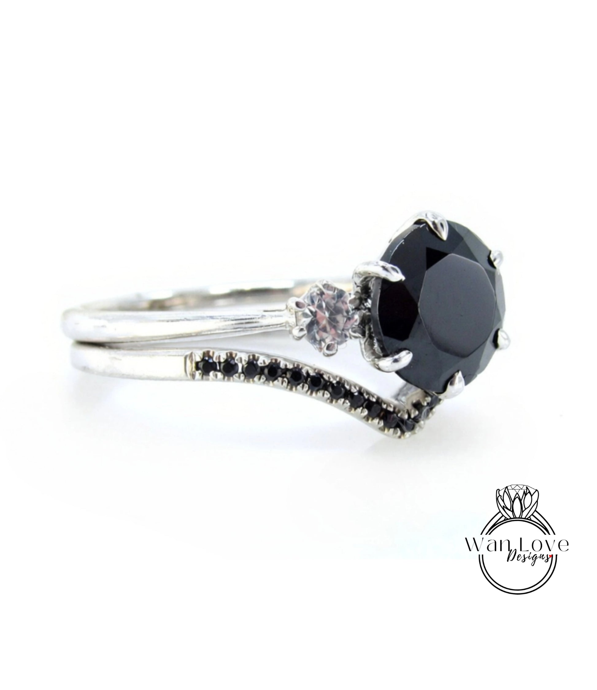 A silver ring with a large black gemstone, possibly a diamond, and a smaller gemstone. The ring has a curved band and small black stones on the sides.