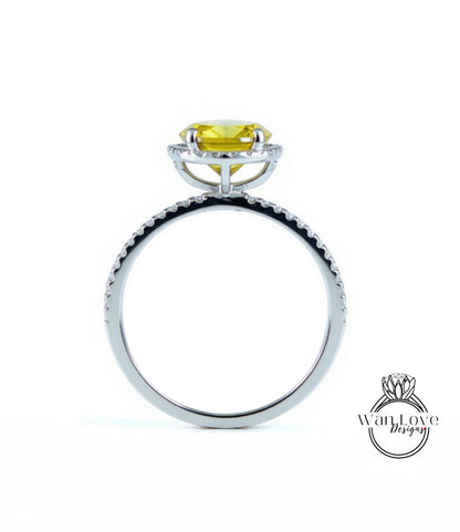 A silver ring with a yellow gemstone, possibly a diamond, set in the center.