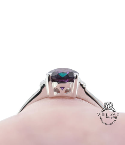 A close-up view of a silver ring with a large purple gemstone, likely an amethyst, set in the center.