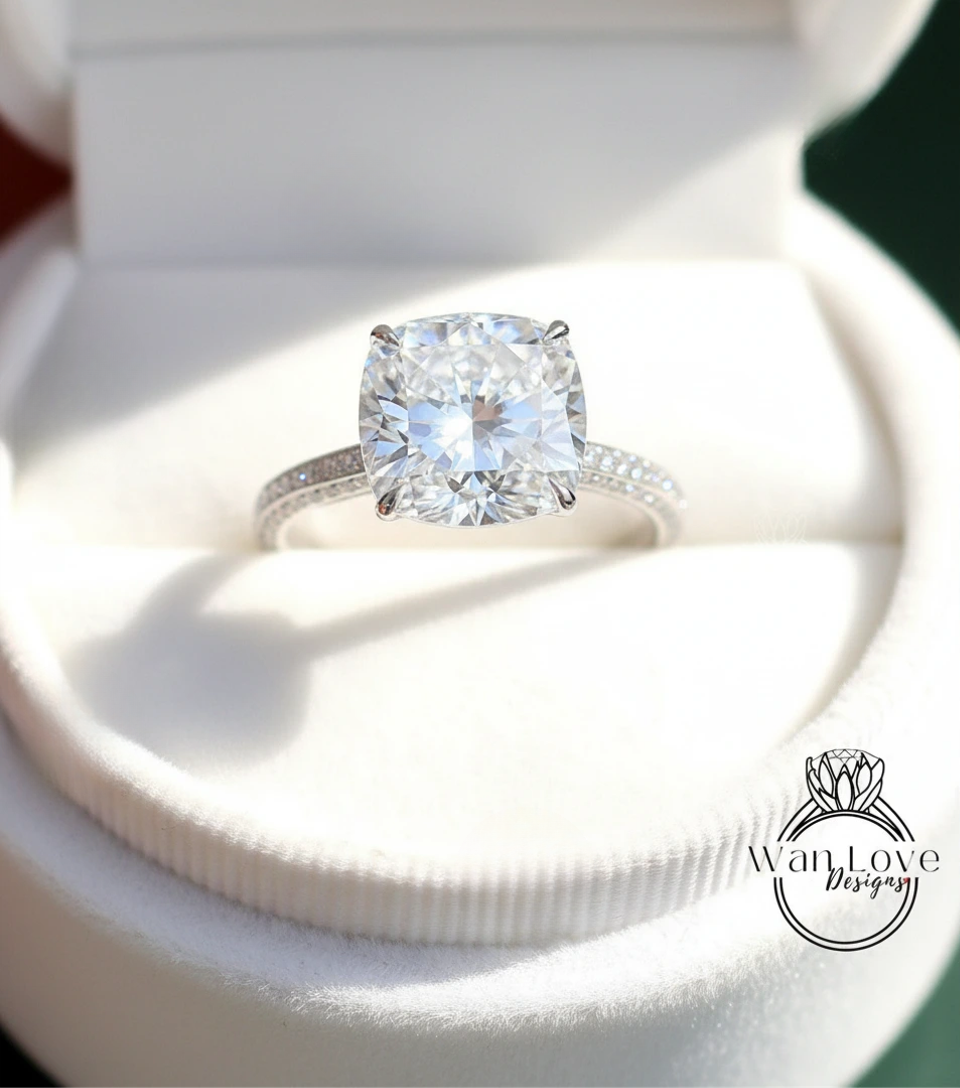 A large, clear diamond engagement ring is displayed in a white box, showcasing its sparkling cut and brilliant clarity.