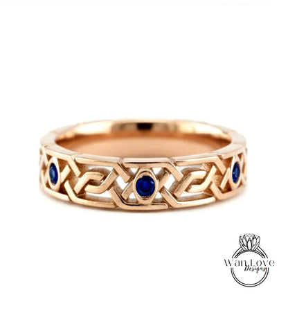 A gold ring with a Celtic knot design and blue gemstones.