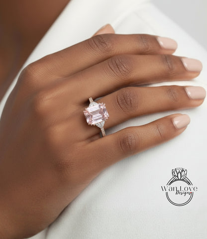 A close-up of a hand wearing a large, pink gemstone ring on the ring finger.