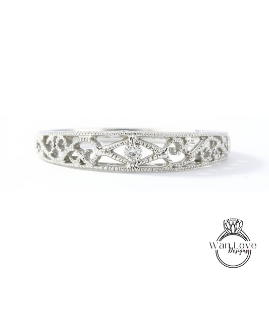 A silver band with an intricate, decorative design featuring a floral pattern and small diamonds.