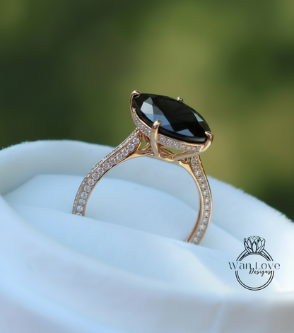 A gold ring with a large black gemstone, likely a diamond, set in a gold band with small diamonds.