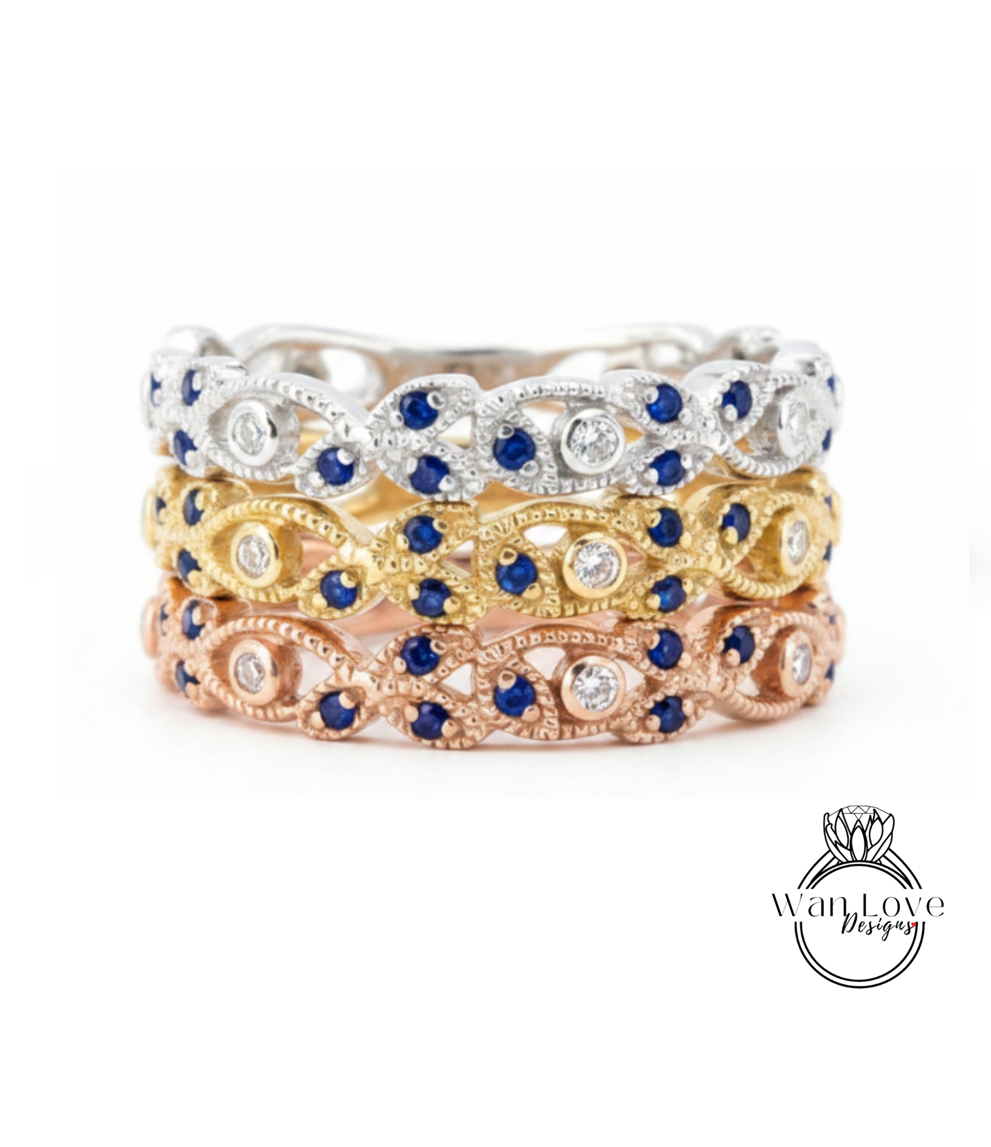 A ring with three distinct layers of rings, each with a unique design and color. The topmost ring is silver, the middle one is gold, and the bottom one is pink. The rings are adorned with blue and white gemstones, adding a touch of elegance and sophistication to the overall design.