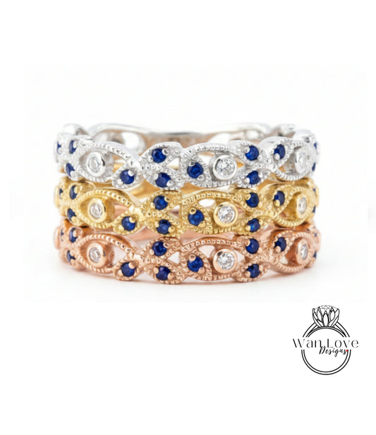 A ring with three distinct layers of rings, each with a unique design and color. The topmost ring is silver, the middle one is gold, and the bottom one is pink. The rings are adorned with blue and white gemstones, adding a touch of elegance and sophistication to the overall design.
