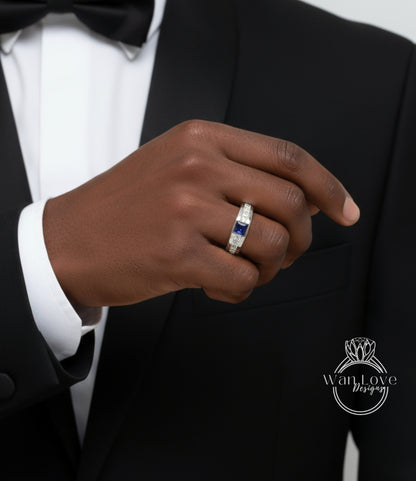 A close-up of a person's hand wearing a ring on the ring finger, with a black suit jacket visible in the background.