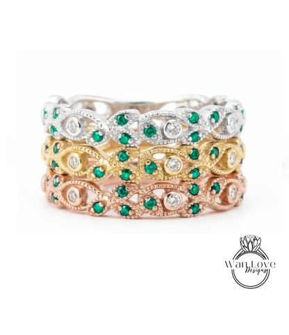 A stack of three rings with green gemstones and diamonds set in various colored metals, including silver, gold, and rose gold.