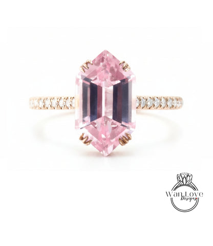 A pink gemstone engagement ring with a gold band and small diamonds around the band.