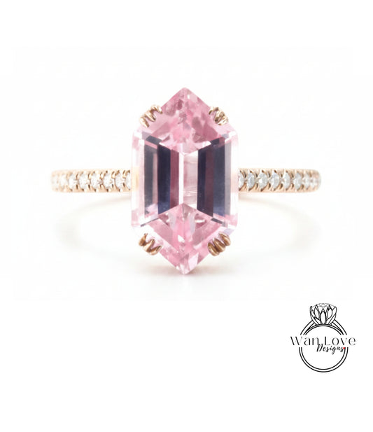 A pink gemstone engagement ring with a gold band and small diamonds around the band.