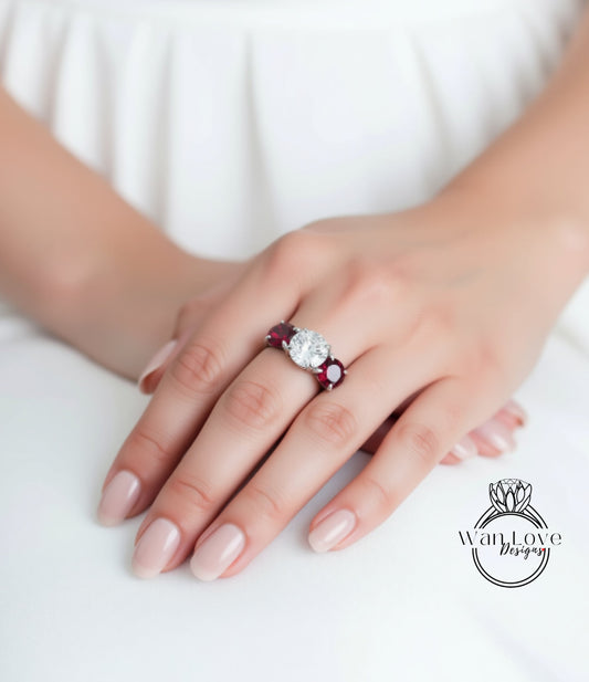 A close-up of a person's hand wearing a ring with a large diamond and a smaller diamond on either side.