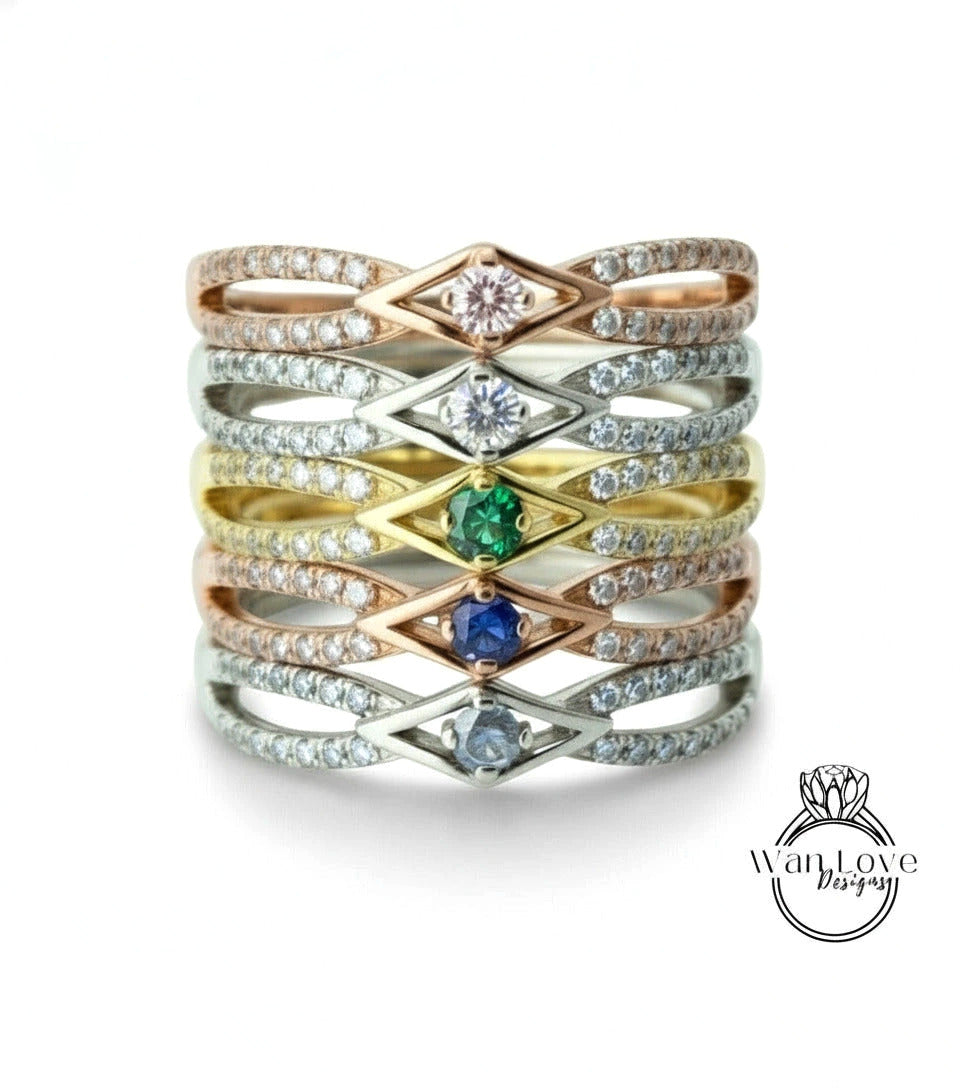 A stack of rings with various gemstones and designs, including diamonds and colored stones.