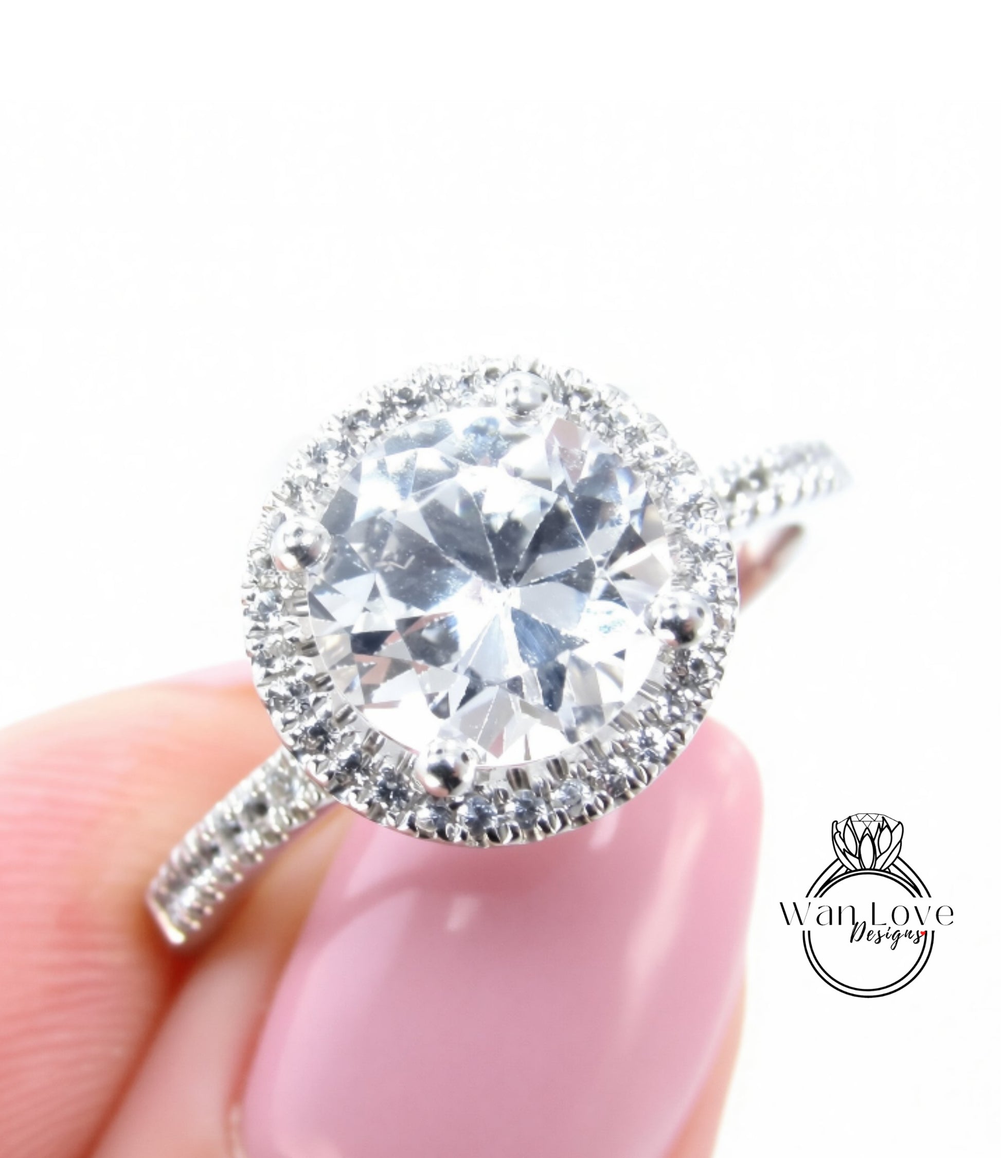 A close-up image of a person's hand holding a diamond engagement ring with a large, clear gemstone set in a halo of smaller diamonds.