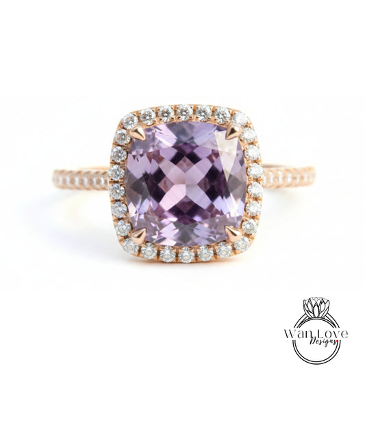 A close-up image of a gold ring with a large, purple gemstone set in the center, surrounded by a halo of smaller diamonds.