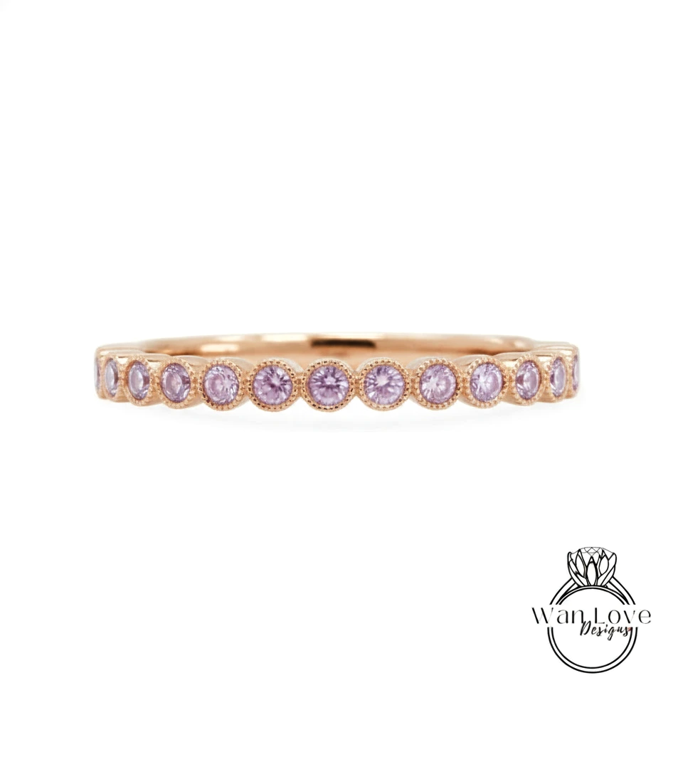 A gold band ring with a row of small, round, purple gemstones set in the center.