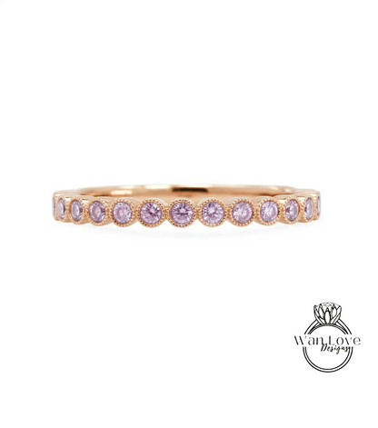 A gold band ring with a row of small, round, purple gemstones set in the center.