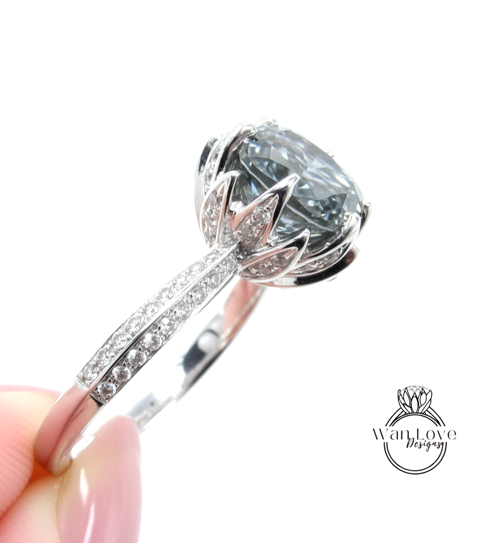 A close-up view of a silver ring with a large, gray gemstone set in the center, surrounded by smaller diamonds.