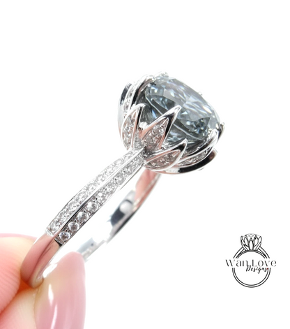 A close-up view of a silver ring with a large, gray gemstone set in the center, surrounded by smaller diamonds.