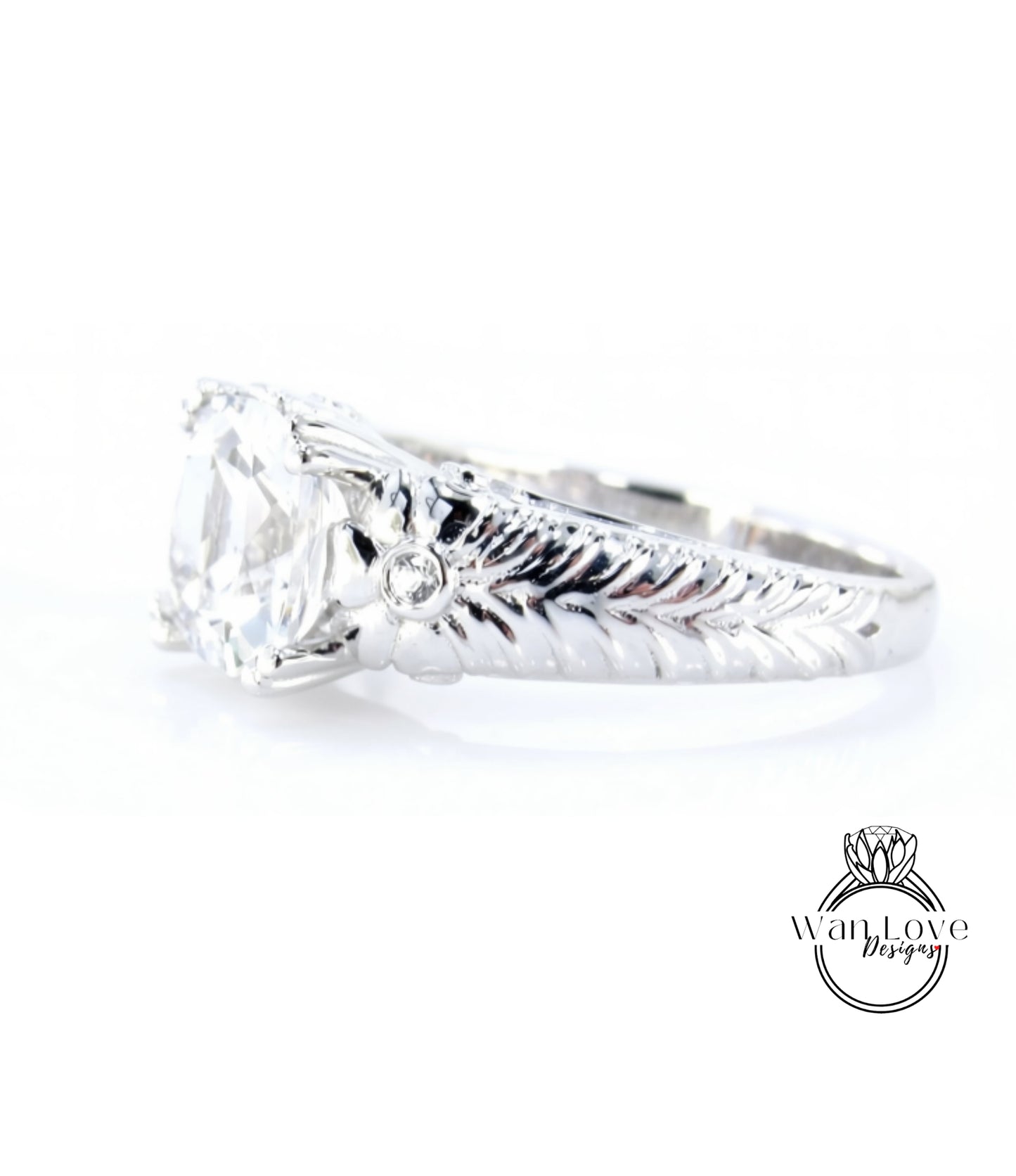 A close-up view of a silver engagement ring with a large central diamond and intricate leaf-like designs on the band.