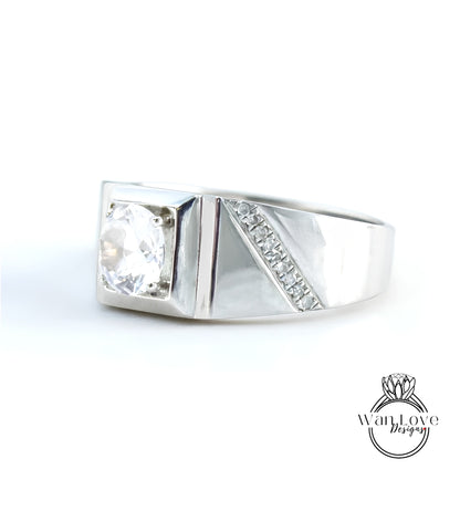 A silver ring with a large diamond set in the center, showcasing a unique design with a diagonal cut and a row of small diamonds along the side.