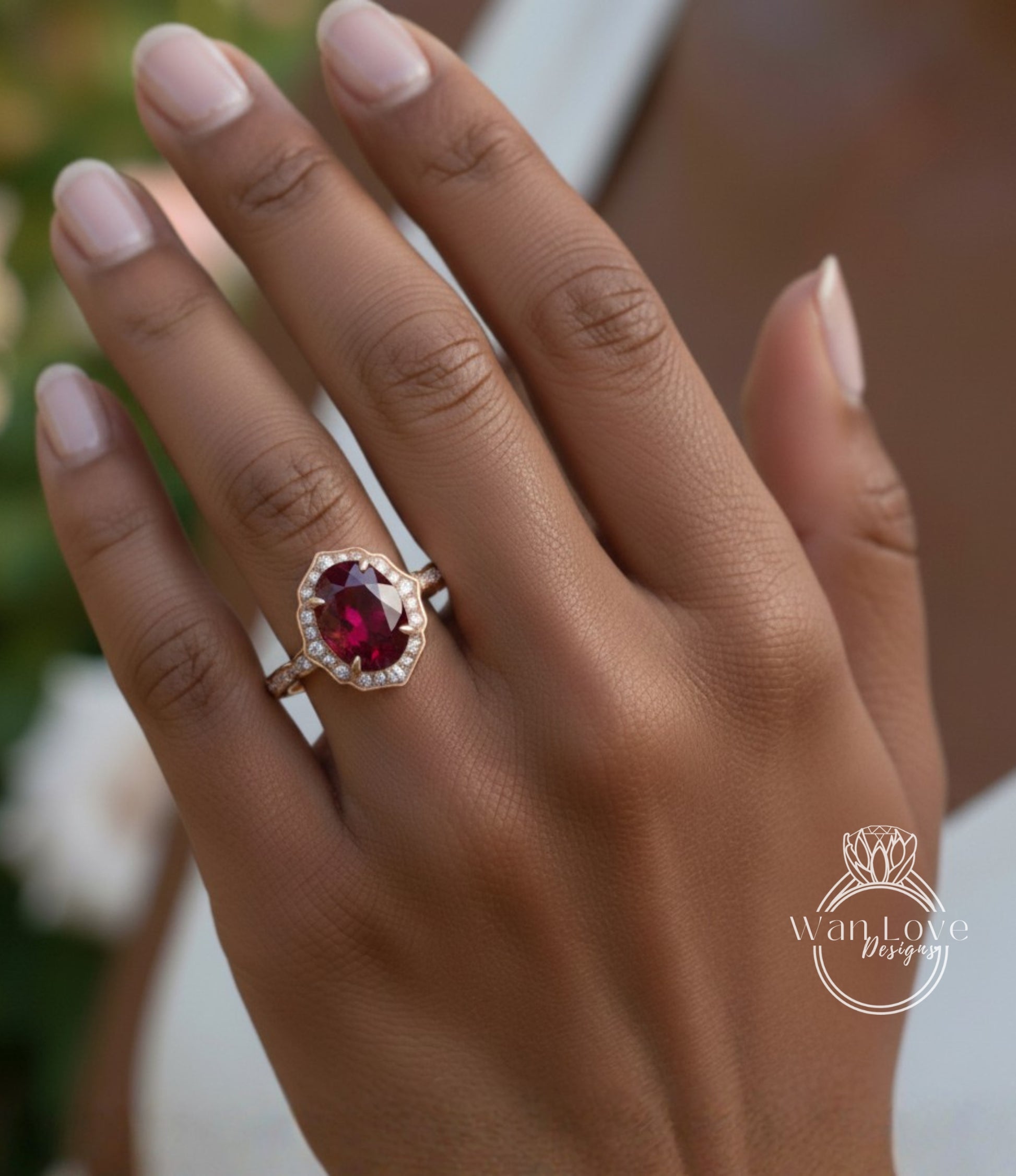 A close-up of a person's hand wearing a gold ring with a large, deep red gemstone.