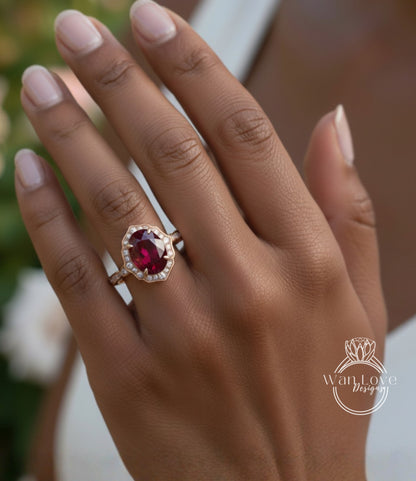A close-up of a person's hand wearing a gold ring with a large, deep red gemstone.