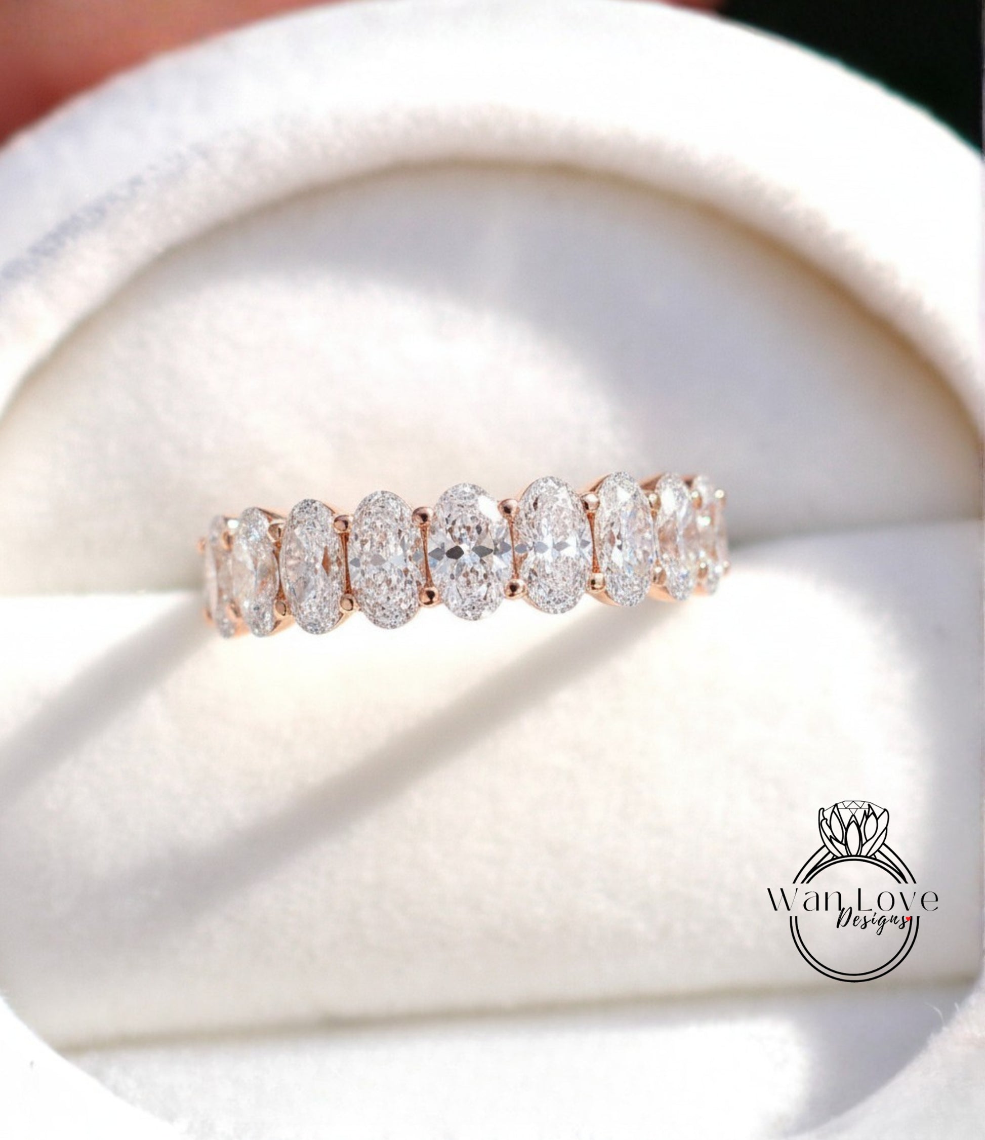 A close-up image of a diamond ring with a row of oval-shaped diamonds set in a gold band.
