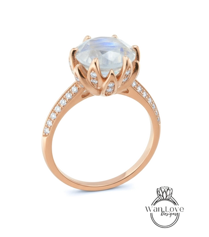 A rose gold ring with a large blue gemstone, likely a moonstone, set in a delicate flower-like design.