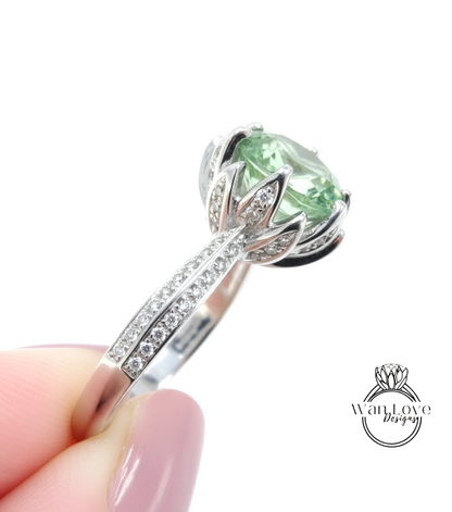 A close-up of a silver ring with a large, green gemstone, possibly a diamond, set in a decorative design.