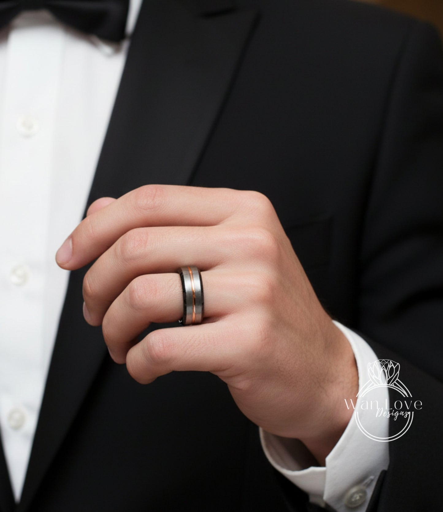 A close-up of a person's hand wearing a black tuxedo jacket and a ring on the finger.
