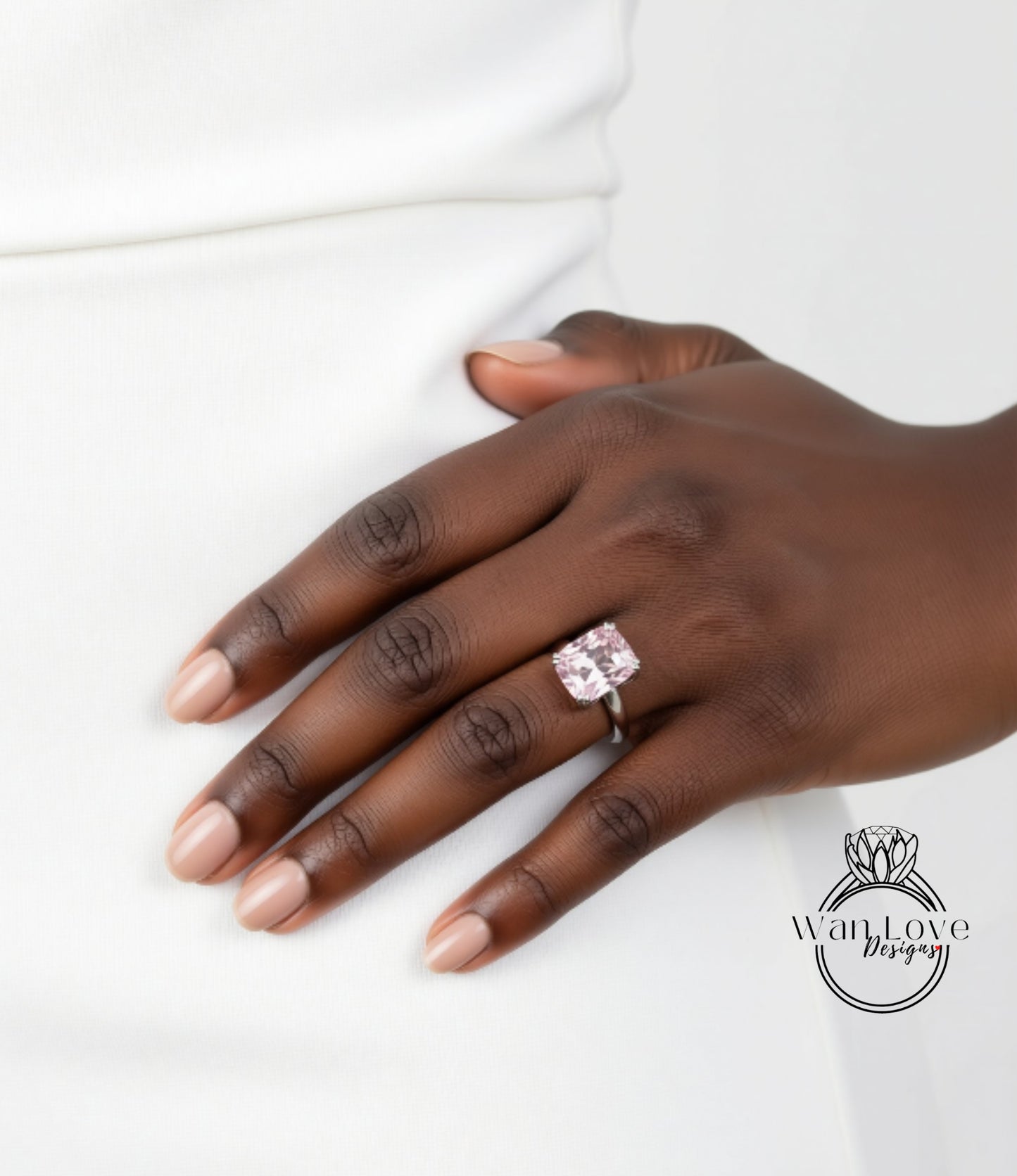 A close-up of a hand wearing a large, pink diamond ring.